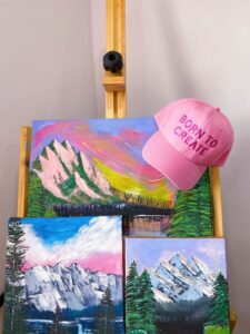 gorra rosa y cuadros de paisajes con acrílicos